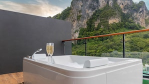 A modern bathroom with a bathtub, a glass of champagne, and a view of a mountainous landscape. - Panan Krabi Resort (Krabi)