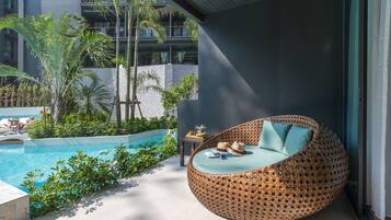 Relax by the pool in a serene outdoor space surrounded by lush greenery and a modern building.