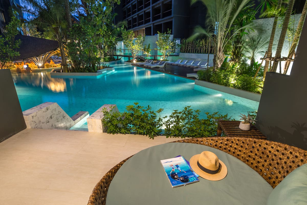 A poolside area with lounge chairs, a wicker sofa, and a magazine.
