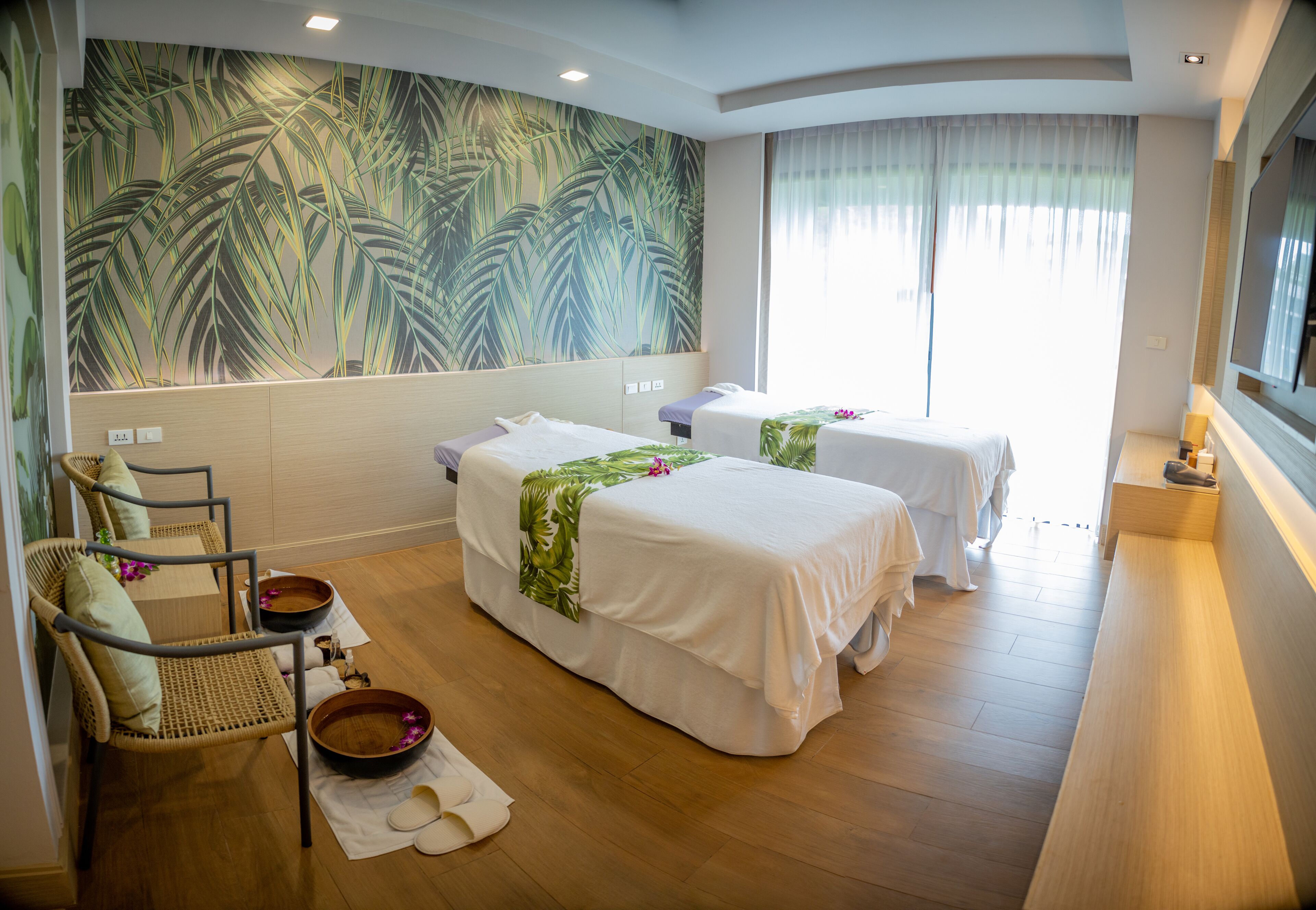 A room with two beds, a massage chair, a wooden floor, and a large wall mural.