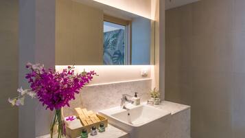 Un baño moderno con una bañera grande, un espejo sobre el lavabo y un jarrón con orquídeas moradas.
