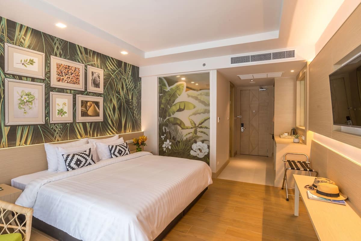 A bedroom with a bed, a nightstand, a chair, a table with a hat, and a mirror.
