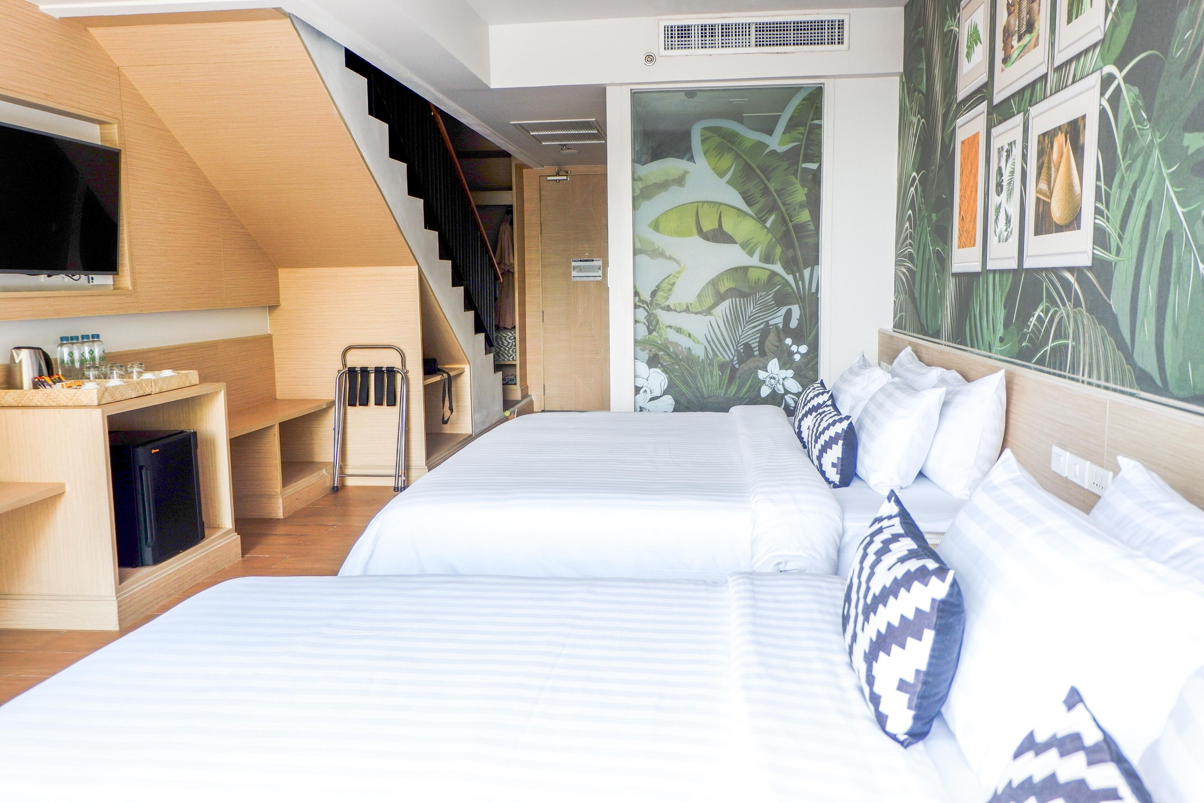 Una habitación de hotel con una cama grande, televisión, zona de cocina y una escalera.