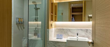 A modern bathroom with a glass shower enclosure, a marble countertop, and a sink with a mirror above it.