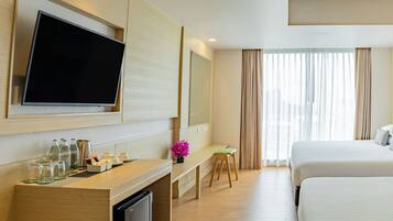 Une chambre d’hôtel équipée d’un téléviseur à écran plat, d’un bureau avec un ordinateur, d’un petit tabouret et de deux lits.