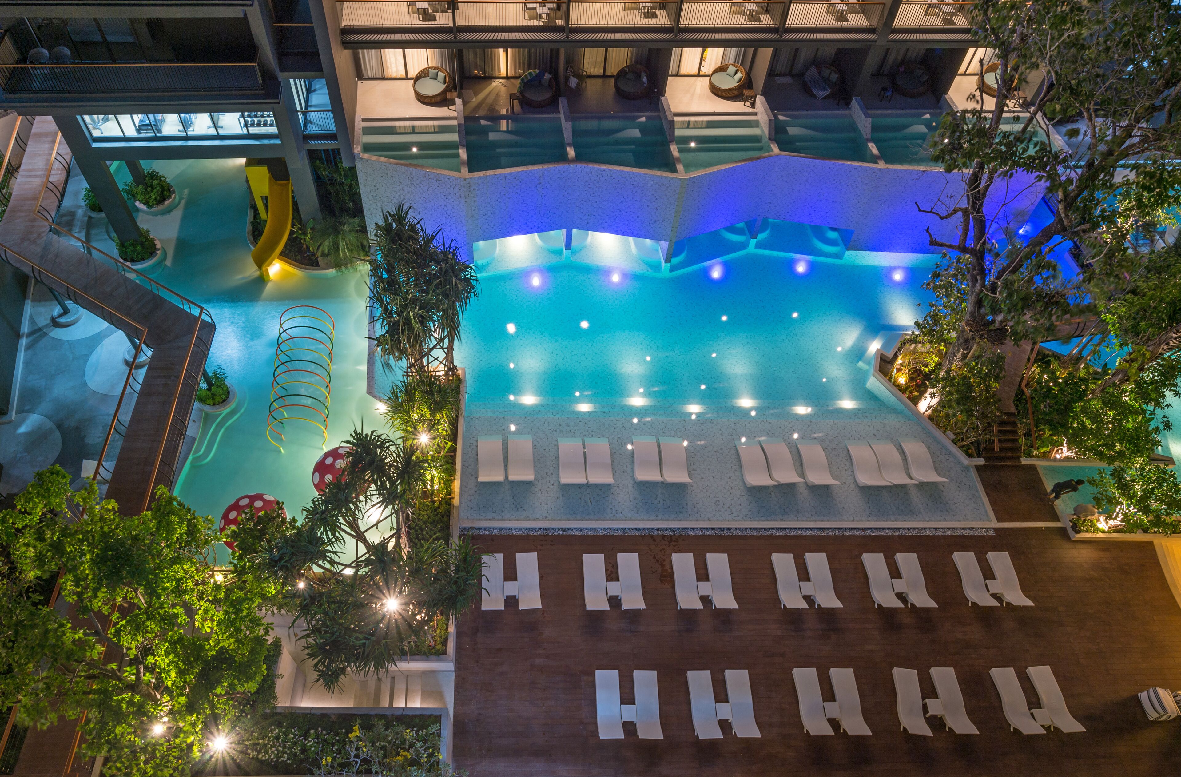 An indoor swimming pool with multiple lanes, lounge chairs, and a seating area with umbrellas.