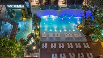 An indoor swimming pool with multiple lanes, lounge chairs, and a seating area with umbrellas.