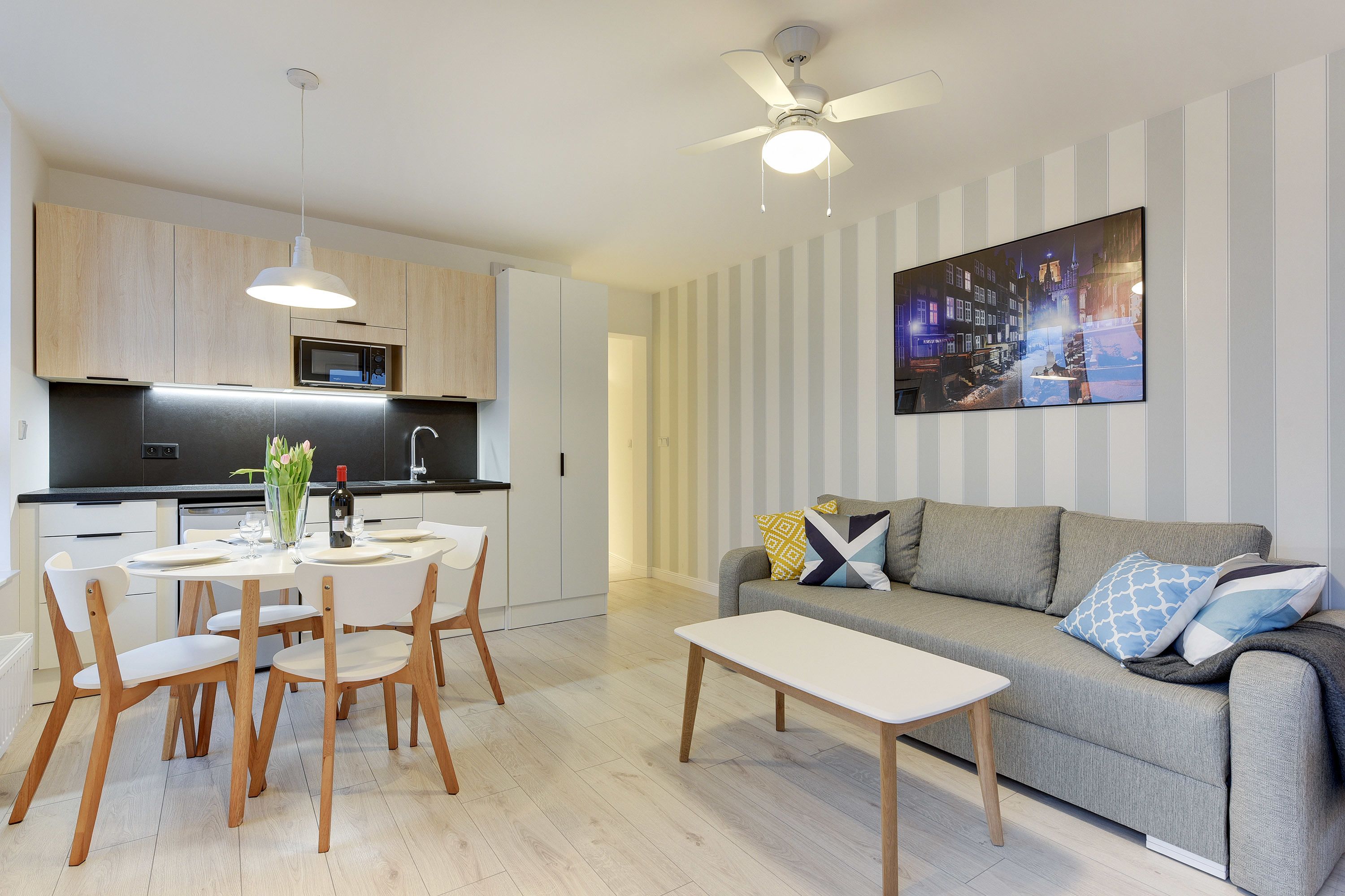 Un salon moderne avec un canapé gris, une table basse blanche et un coin repas comprenant une table ronde et des chaises.
