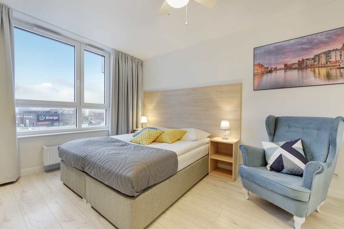 Une chambre d’hôtel avec un lit, une chaise, un tableau et une vue sur la ville.