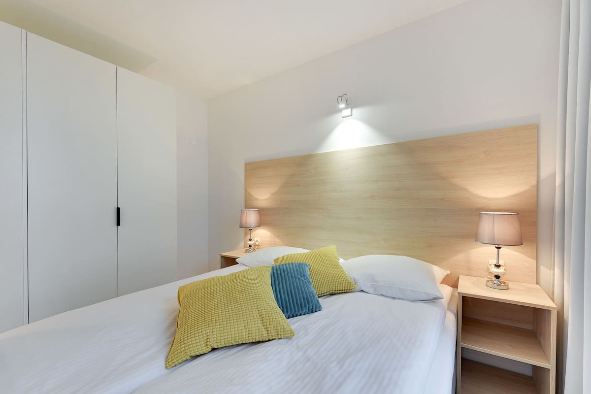 Un lit bien fait, avec des oreillers, une lampe de chevet et une tête de lit en bois.