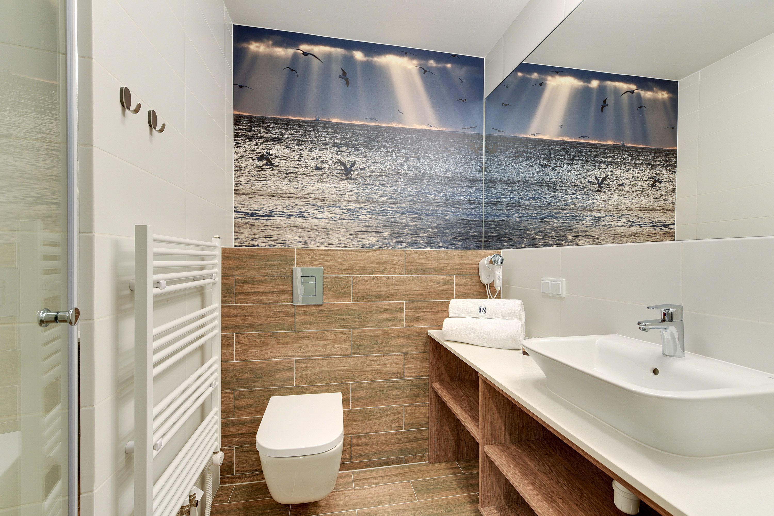 Een moderne badkamer met een houten wastafelmeubel, een witte wastafel en een toilet.
