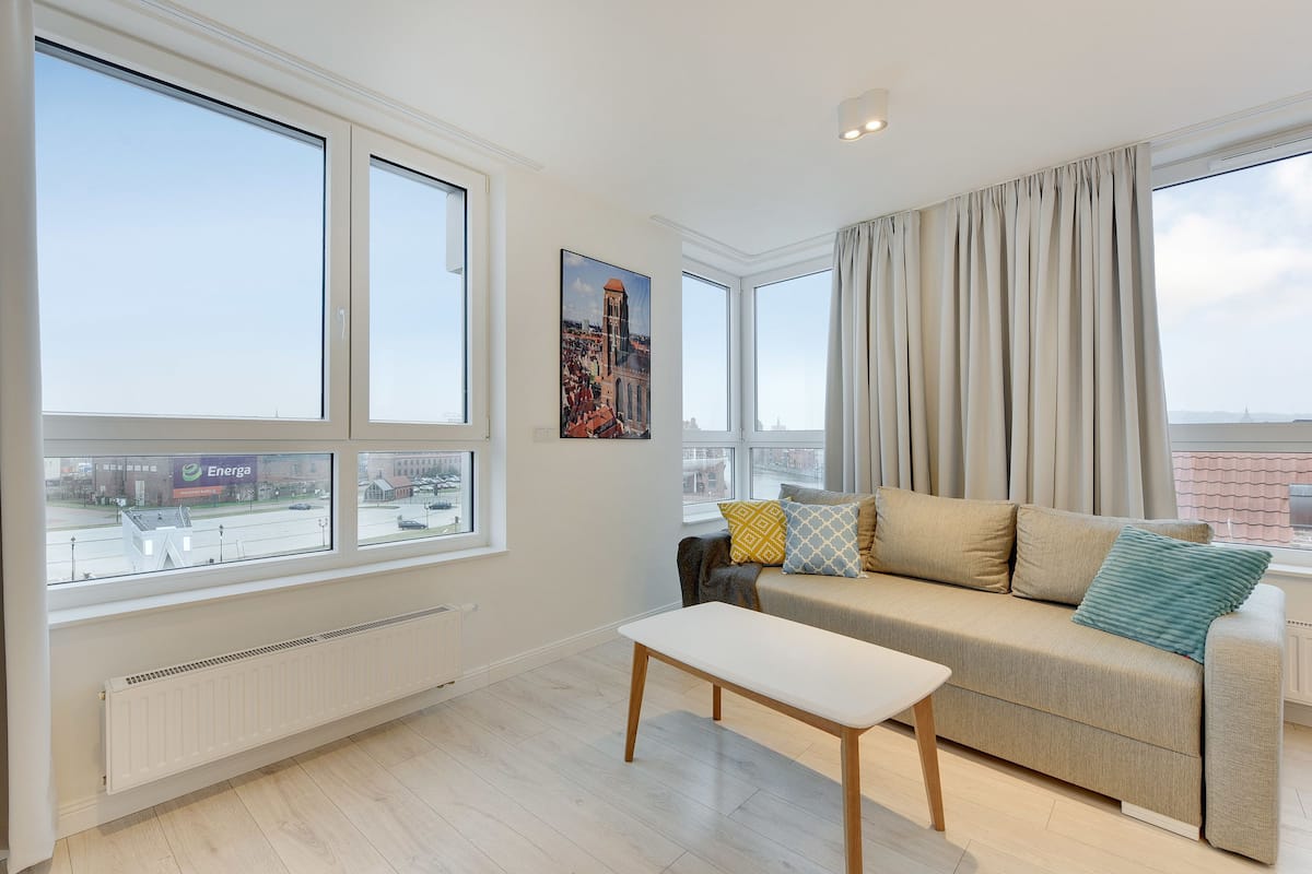 Un salon moderne avec de grandes fenêtres, un canapé, une table et un radiateur.