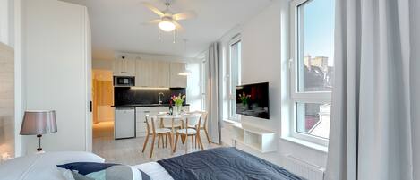 Une chambre d’hôtel moderne dotée d’un grand lit, d’une télévision, d’un coin repas et offrant une vue sur la ville.
