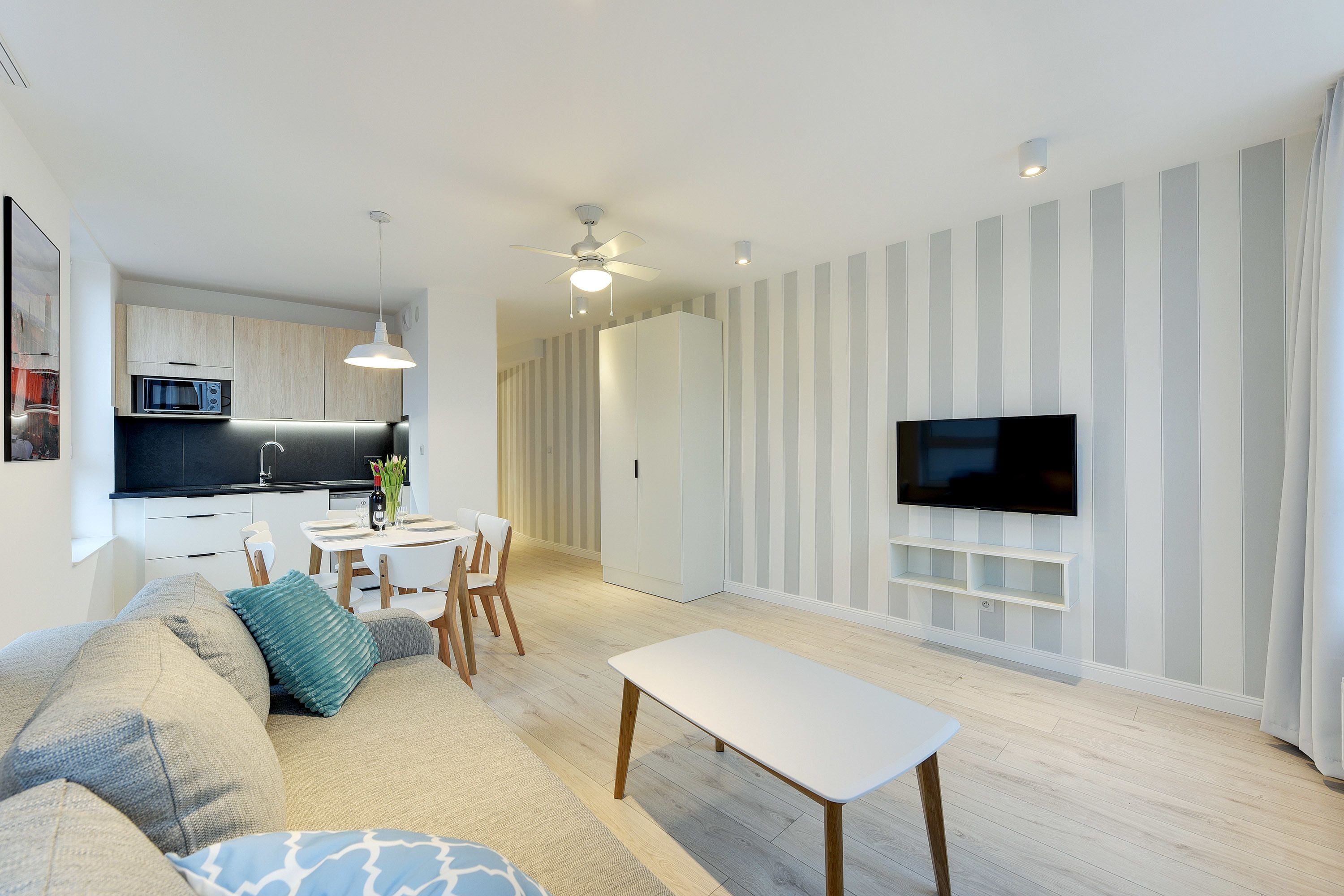 Una sala de estar moderna con un sofá, una mesa de centro y un televisor montado en la pared.