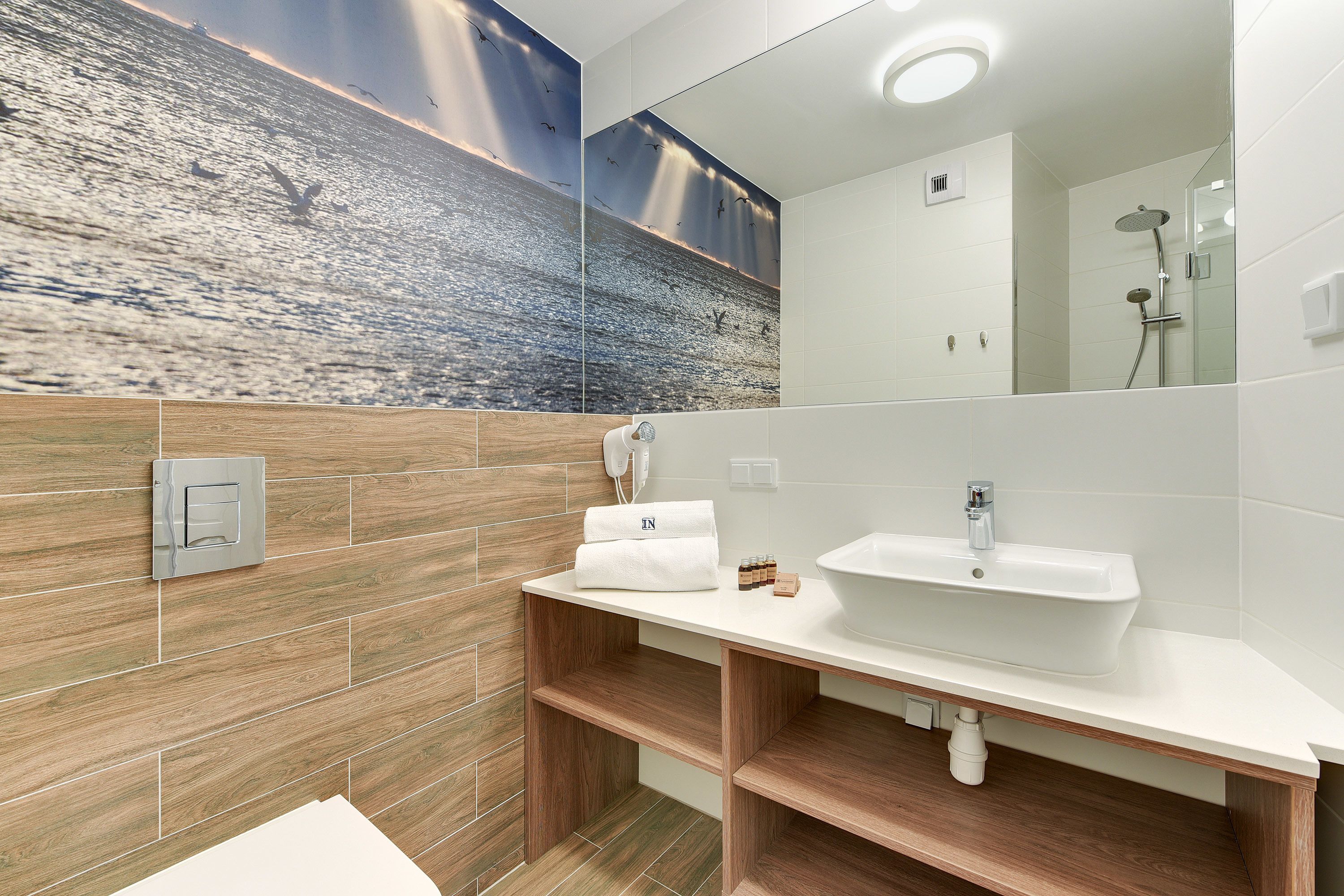 Un bagno moderno con una parete in legno, un lavandino bianco e uno specchio grande.