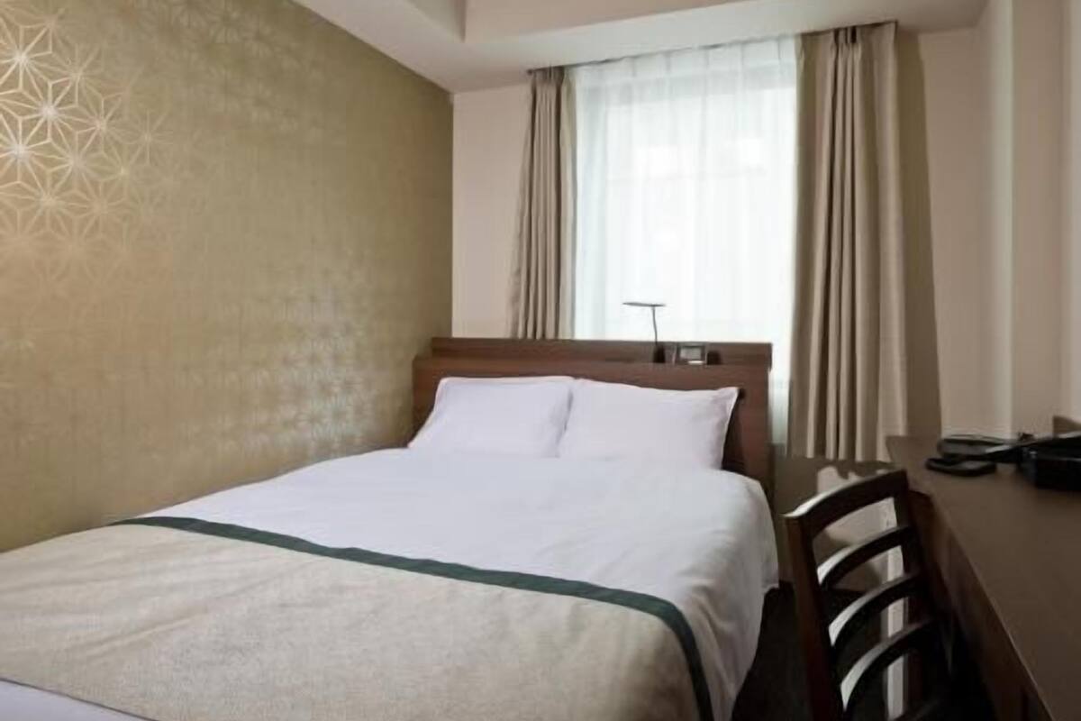 Een hotelkamer met een bed, een bureau en een stoel.