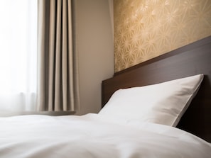 Een net opgemaakt bed met witte beddengoed, een houten hoofdbord en een muur met een geometrisch patroon.
