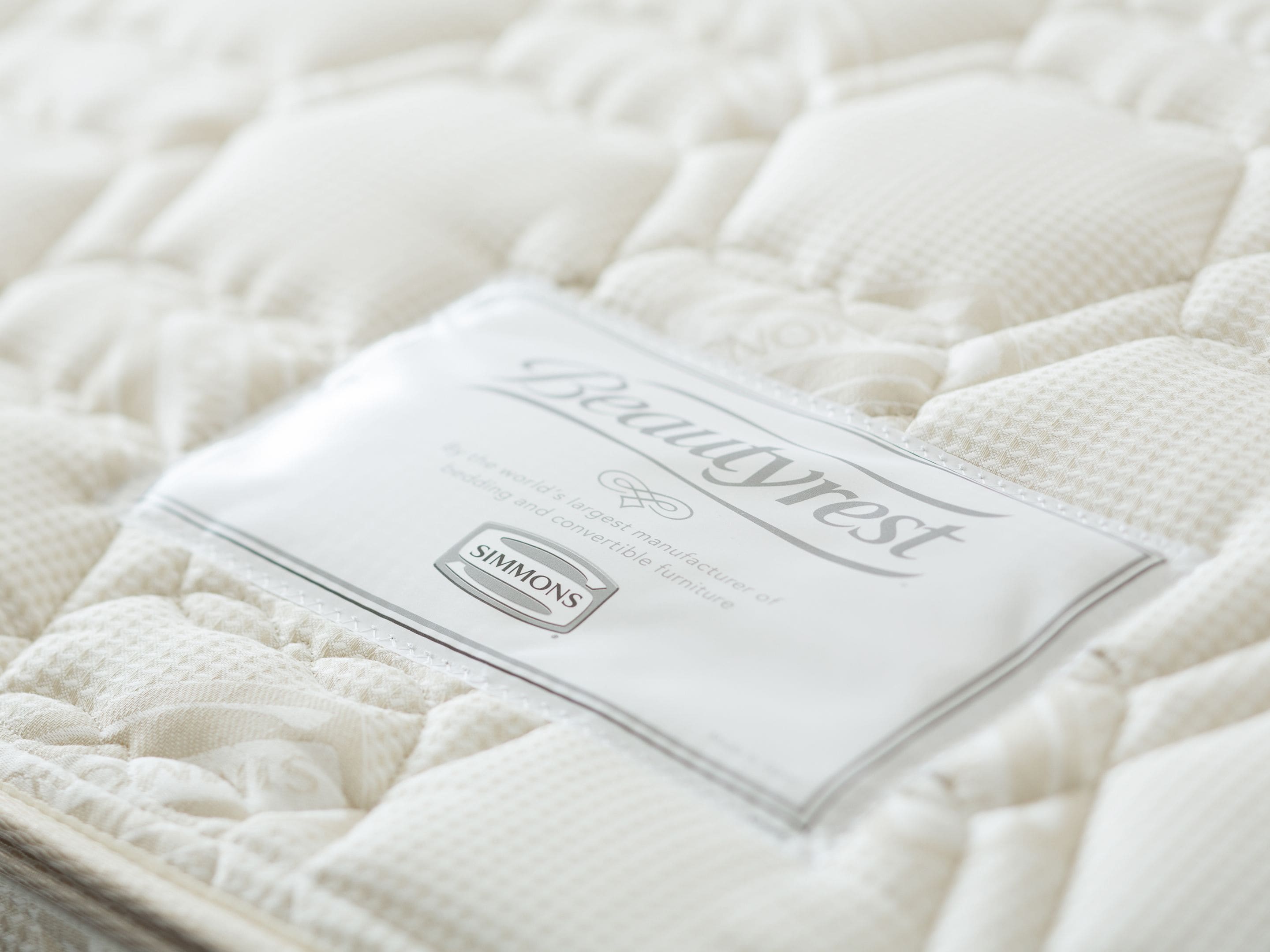 A white mattress with a label indicating it is from Simmons, a manufacturer of wedding and convertible furniture.