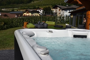 A hot tub with a view of a residential area, including houses and greenery. - Agriturismo Il Tempo delle Mele (Caldes)