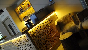 A bar area with a wooden log display and a seating area with a furry chair.