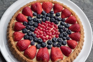 A fruit tart with strawberries, blueberries, and red currants arranged in a circular pattern. - Agriturismo Il Tempo delle Mele (Caldes)