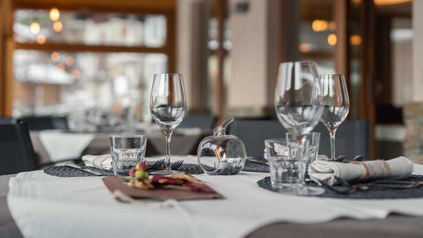 A dining table set with wine glasses, water glasses, and a candle centerpiece.