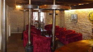 Une pièce avec des fauteuils en velours rouge, un mur en briques et une table en bois.
