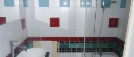 A bathroom with a white sink, a shower, and tiled walls with red and blue accents.