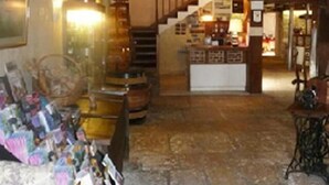 Un intérieur rustique avec un sol en pierre, des poutres en bois, un escalier et un coin bar.
