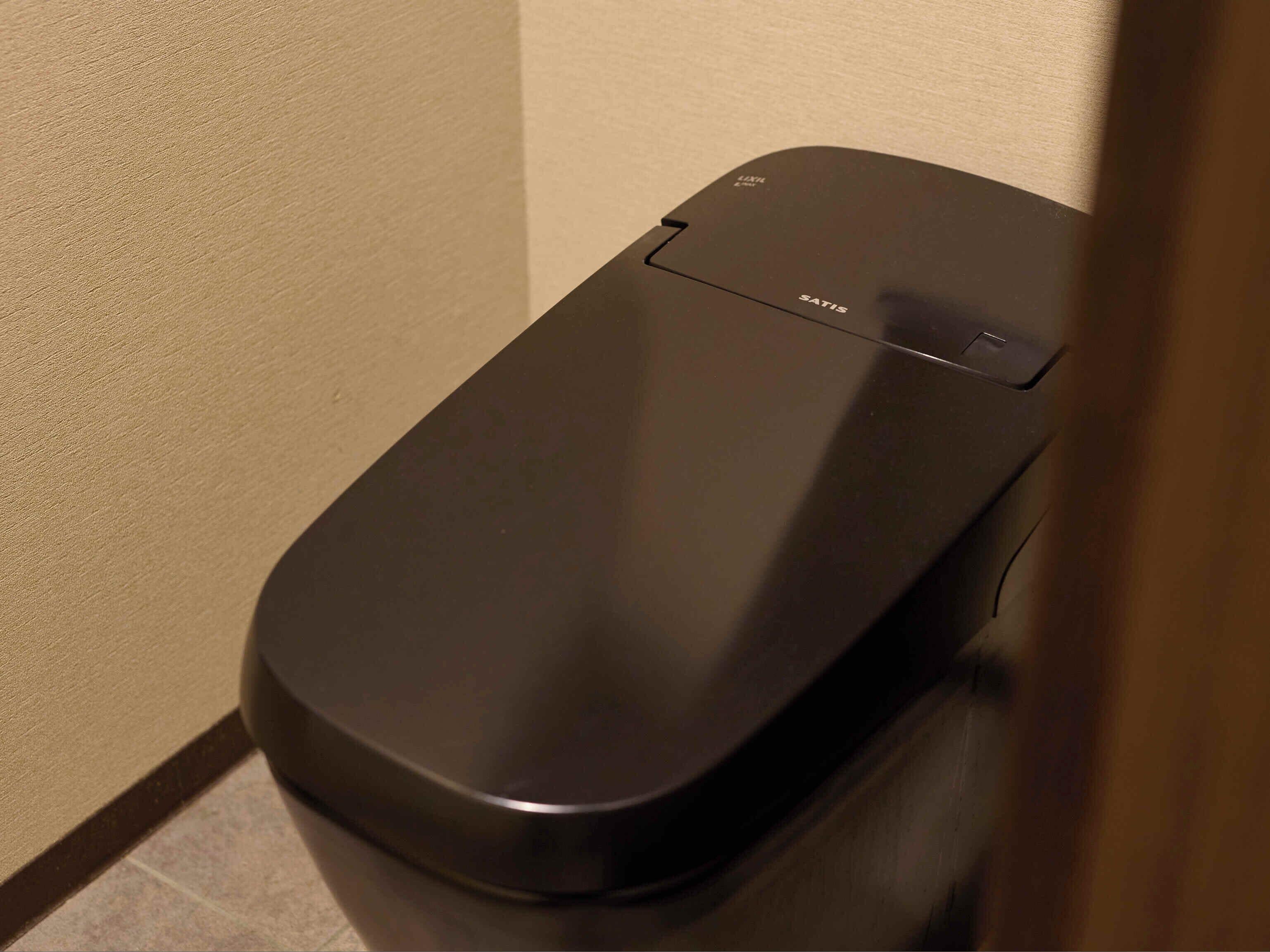 A black, modern, wall-mounted trash bin with the brand name 'SATIS' visible.