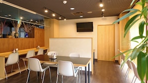 A modern conference room with a wooden table, white chairs, and a large mirror. - Hotel Seishokan (Shizuoka)