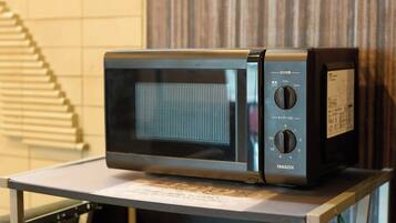 A black microwave on a metal cart with a label underneath.