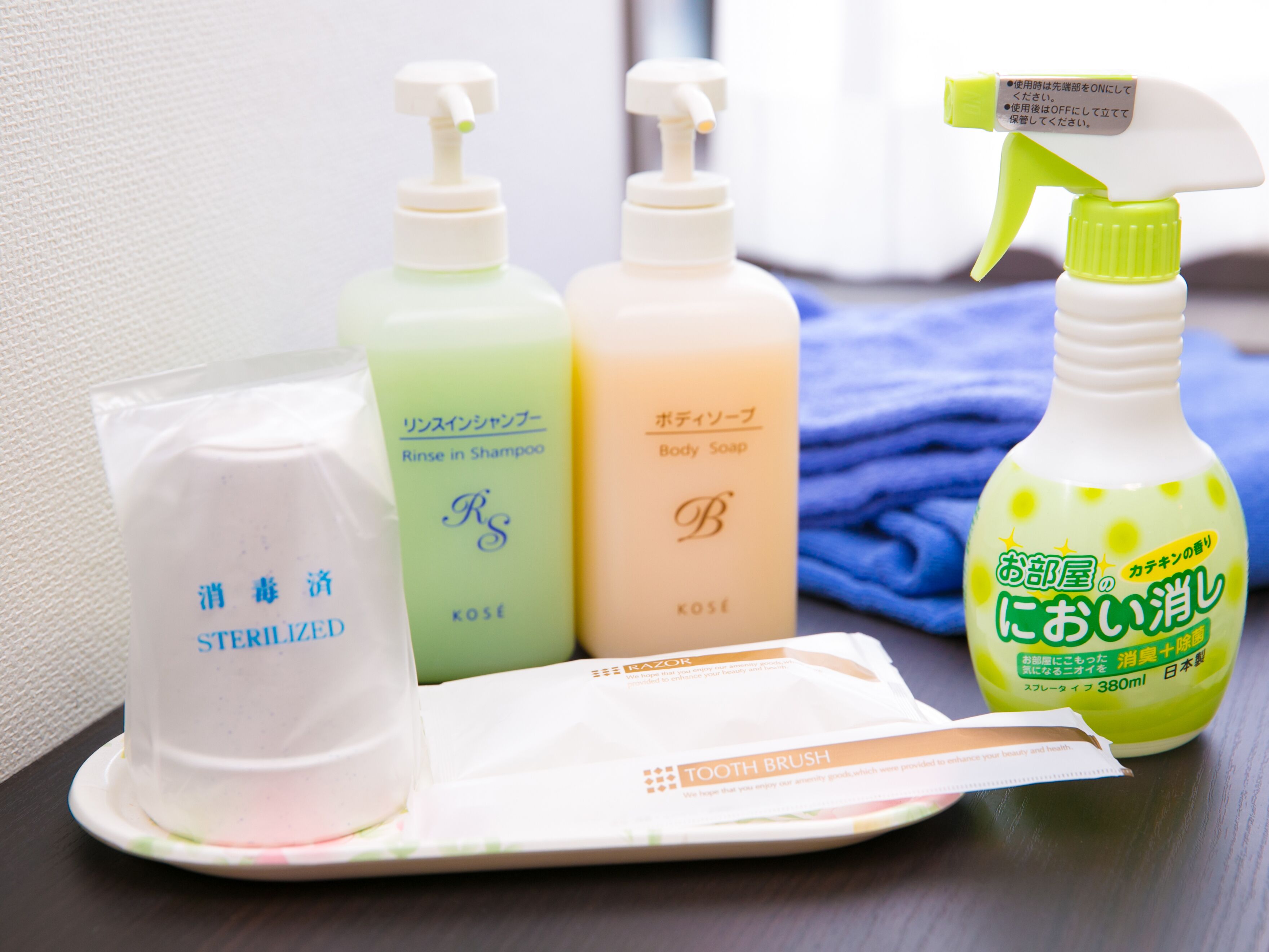 A set of toiletries on a table including a bottle of body soap, a bottle of shampoo, a bottle of hand sanitizer, and a toothbrush.