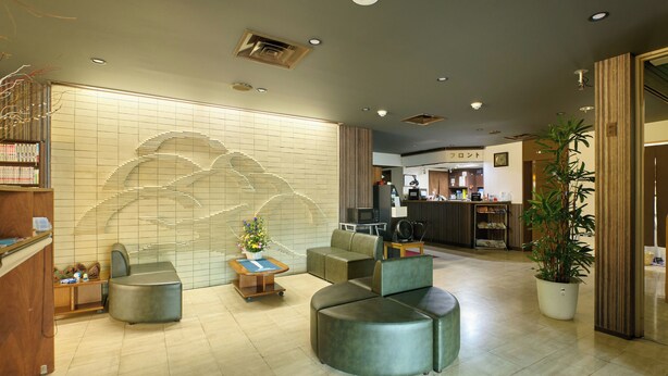 A modern lobby with a reception desk, seating area, and a large wall art piece. - Hotel Seishokan (Shizuoka)