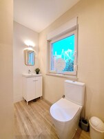 A bathroom with a toilet, sink, and mirror.