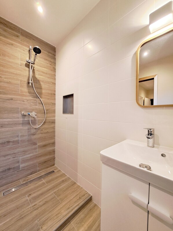Un baño moderno con ducha, lavabo y espejo.
