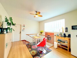 Una cucina compatta con zona pranzo, pavimento in legno, ventilatore a soffitto e una finestra che offre luce naturale.
