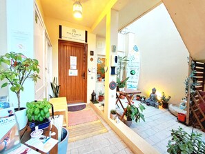 Un espace d’accueil avec une porte en bois, des plantes en pot et un tapis de yoga.