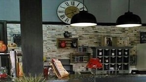 A lobby with a stone wall, a clock, and a table with a lamp. - Au Cheval Blanc (Saint-Amarin)