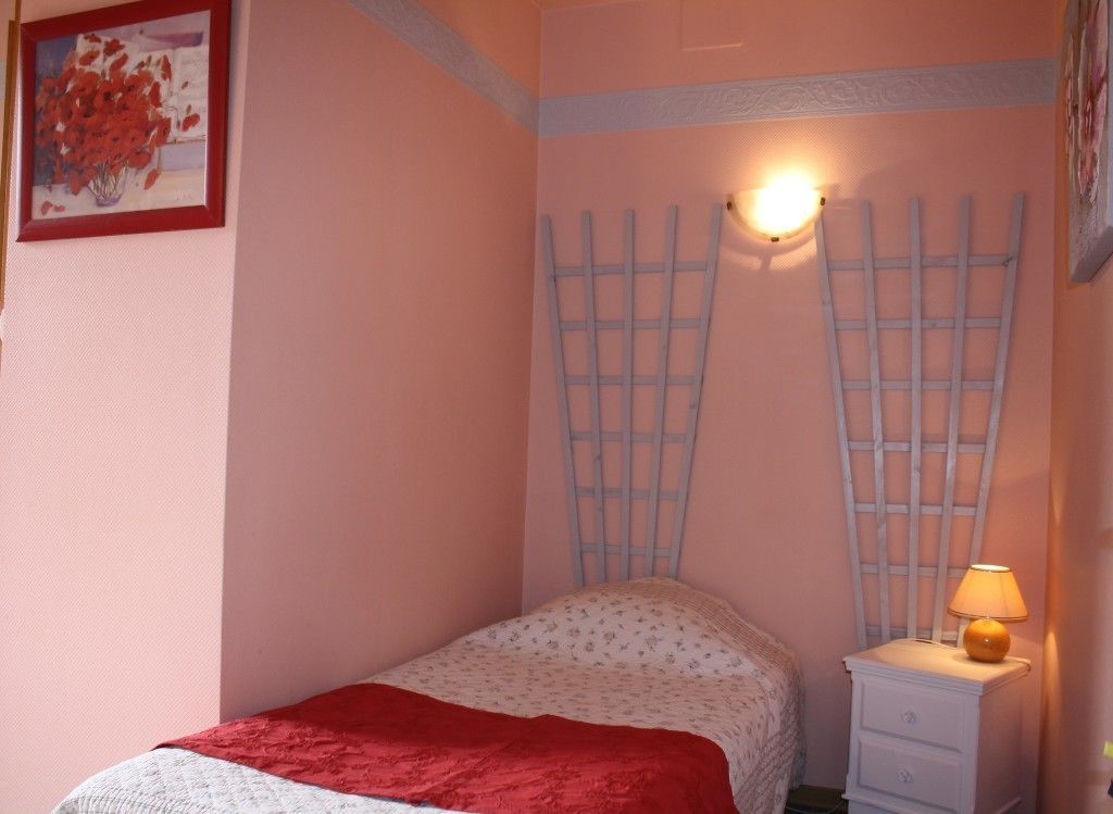 Une chambre à coucher avec un lit, une table de chevet avec une lampe et un luminaire fixé au mur.
