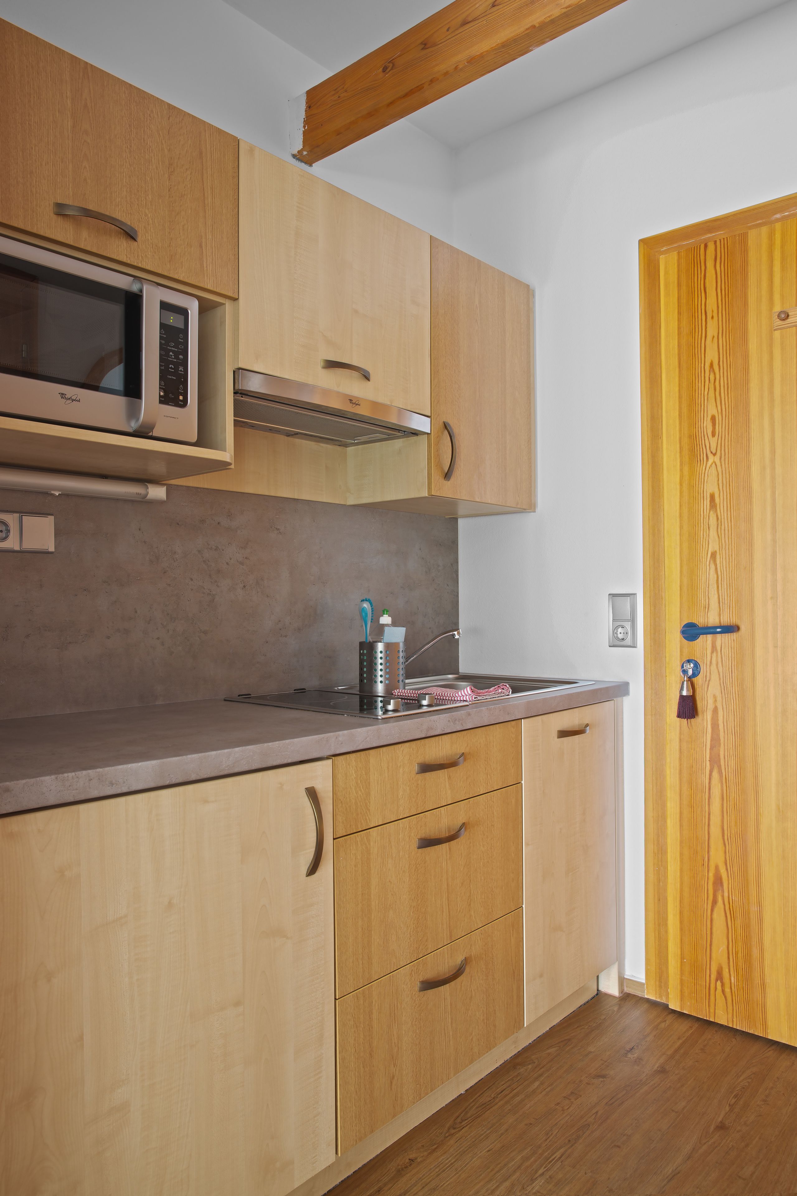 A kitchen with wooden cabinets, a microwave, and a sink.