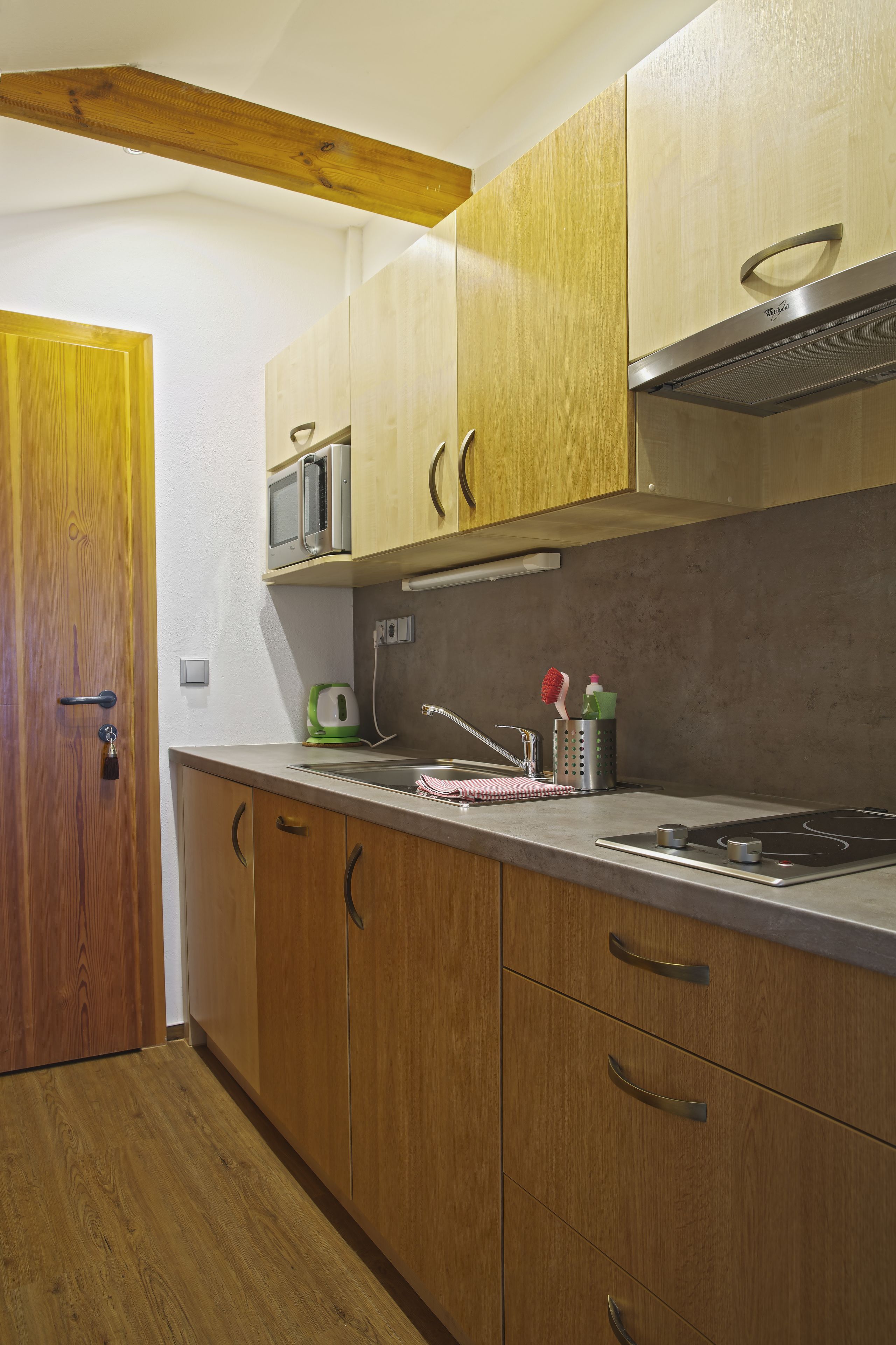 Una cucina con mobili in legno, un forno a microonde, un fornello e un lavello.