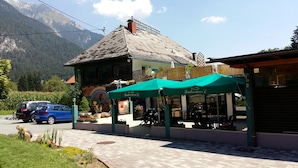 Un restaurante al pie de la montaña con terraza y vistas a las montañas.