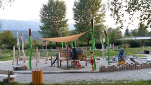 Un parque infantil con estructuras para escalar, una casita de madera y un mural.