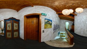 Un pasillo curvo con puertas de madera, una escalera y un banco.