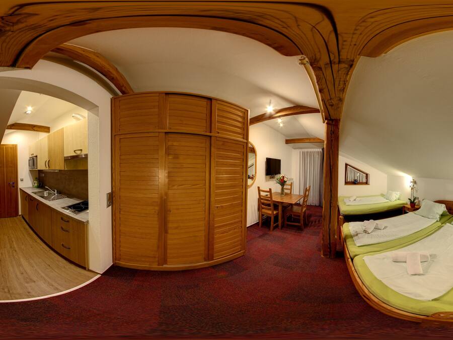 Una habitación con un armario de madera, una cama, un escritorio con una silla y una mesita de noche con una lámpara.
