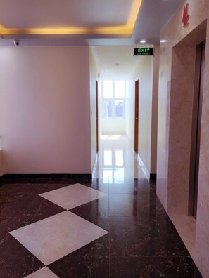 A hotel hallway with a checkered floor pattern, a visible exit sign, and a door marked with the number 4.