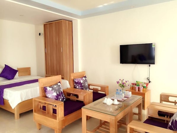 A hotel room with a bed, two wooden chairs, a small table, a TV, and a wardrobe.