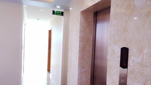 A modern elevator with a metallic finish, a wall-mounted control panel, and a marble-patterned wall. - Lavender Hotel (Hai Phong)