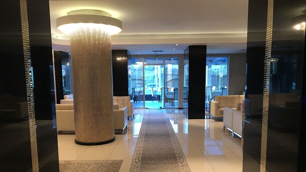 A modern hotel lobby with a central column, white sofas, and a patterned rug. - Pen Hotel (Istanbul)
